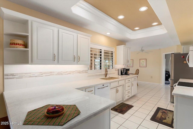 kitchen with sink, light tile patterned floors, a tray ceiling, white dishwasher, and white cabinets