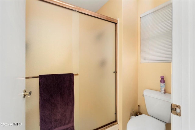 bathroom with a shower with door and toilet