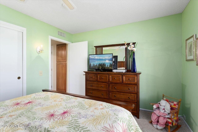 carpeted bedroom with ceiling fan and a textured ceiling