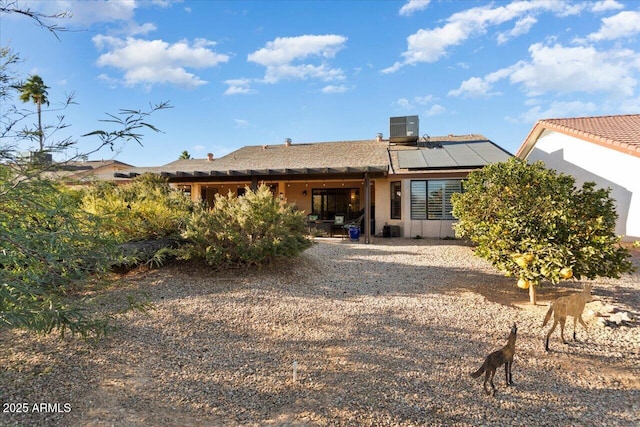 rear view of property featuring cooling unit and solar panels