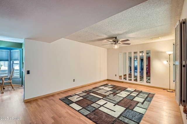 empty room with a textured ceiling, light hardwood / wood-style flooring, and ceiling fan