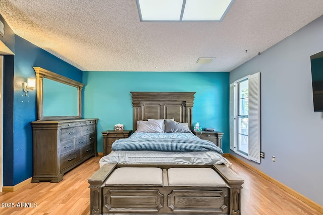 bedroom with a textured ceiling and light wood-type flooring