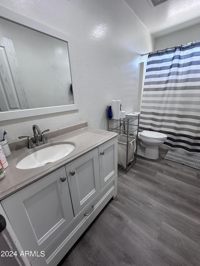 bathroom featuring wood-type flooring, toilet, and vanity