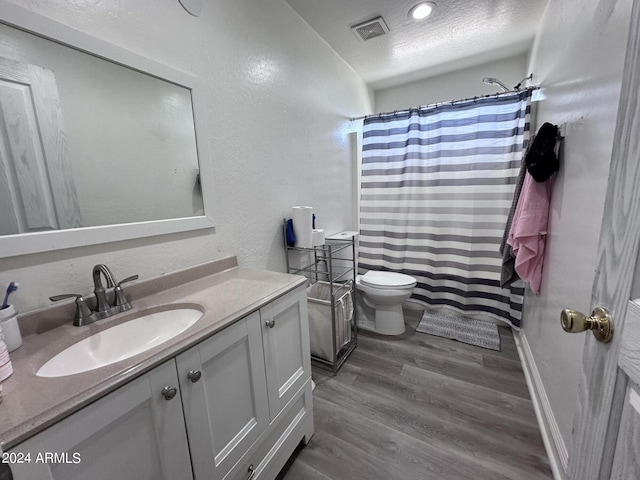 bathroom featuring toilet, vanity, wood-type flooring, and a textured ceiling