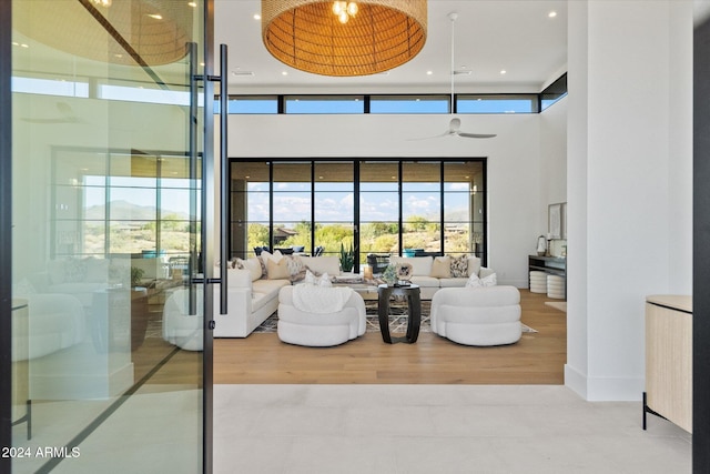 living room with ceiling fan, wood-type flooring, and a high ceiling