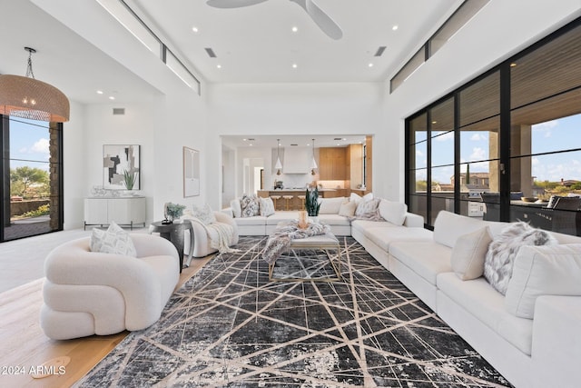 living room featuring a high ceiling, hardwood / wood-style flooring, and ceiling fan