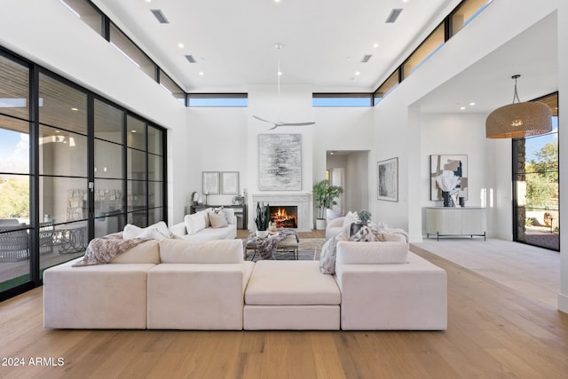 living room featuring ceiling fan, light hardwood / wood-style flooring, and a towering ceiling