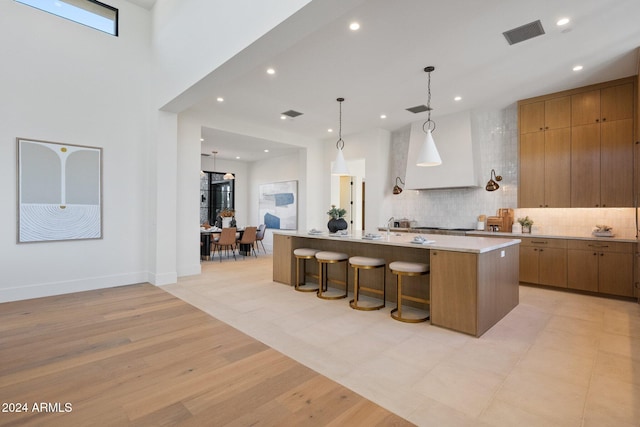 kitchen featuring a breakfast bar area, a large island, pendant lighting, and light hardwood / wood-style floors