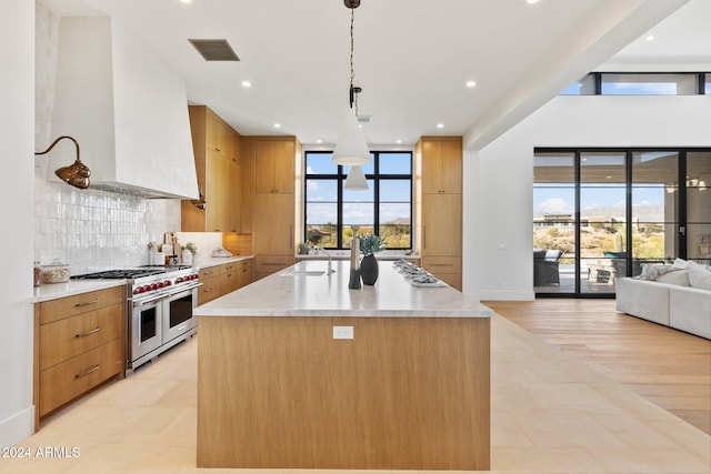 kitchen with a wealth of natural light, hanging light fixtures, double oven range, and light wood-type flooring