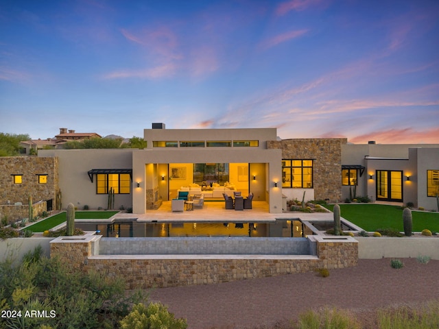 9940 E Aleka Way, Scottsdale, AZ 85262 - back of property at dusk with an outdoor hangout area, a patio, and stucco siding