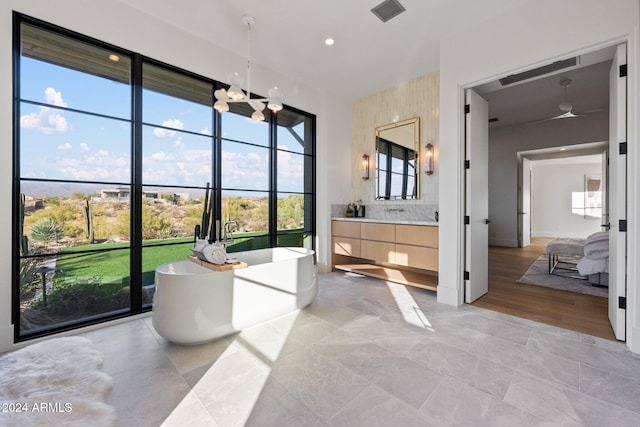 bathroom with a bathtub, vanity, an inviting chandelier, hardwood / wood-style flooring, and decorative backsplash