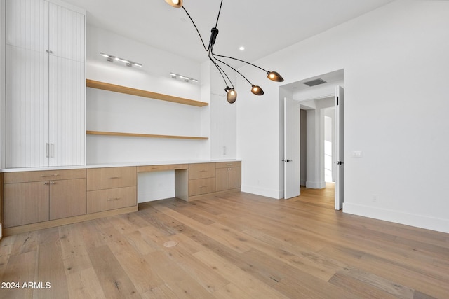 interior space with built in desk and light hardwood / wood-style flooring