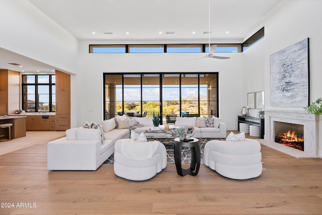 living room featuring a towering ceiling, light hardwood / wood-style flooring, and plenty of natural light