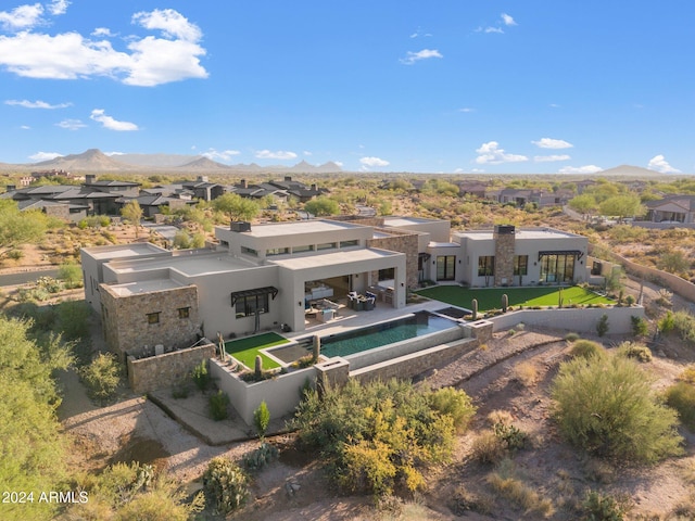 rear view of property with a lawn, a mountain view, and a patio area