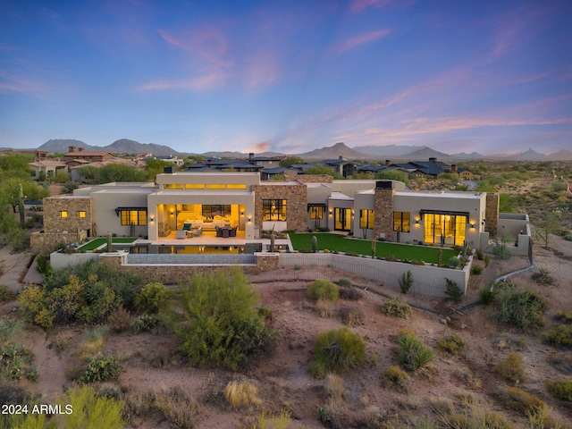 back house at dusk featuring outdoor lounge area, a mountain view, and a yard