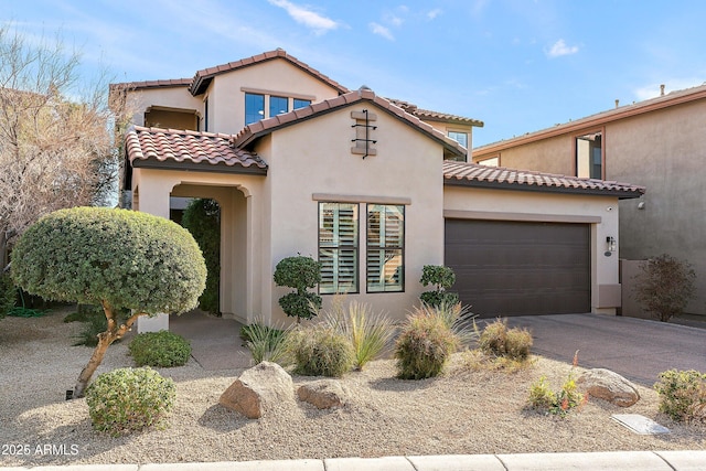 mediterranean / spanish house featuring driveway, a tiled roof, an attached garage, and stucco siding