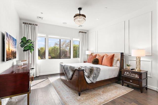 bedroom with a notable chandelier, baseboards, visible vents, and wood finished floors