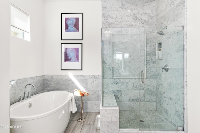 bathroom with wainscoting, a freestanding tub, tile walls, and a shower stall