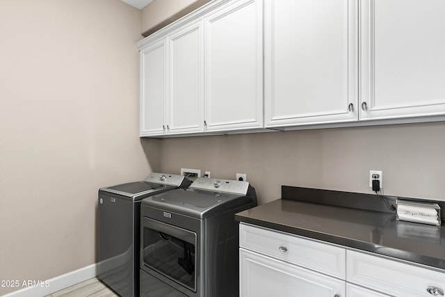 laundry area with light wood finished floors, washing machine and dryer, cabinet space, and baseboards