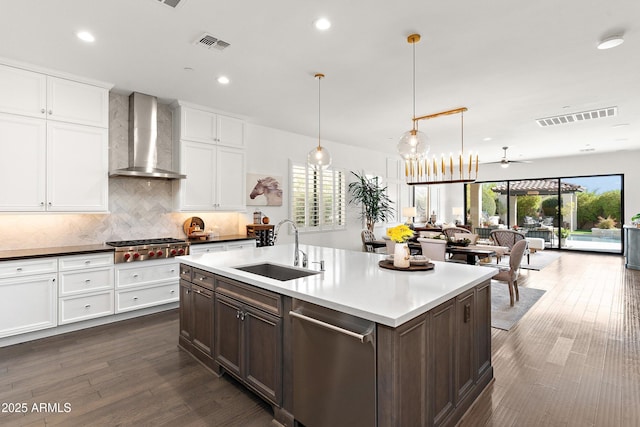 kitchen featuring wall chimney exhaust hood, a sink, visible vents, and pendant lighting