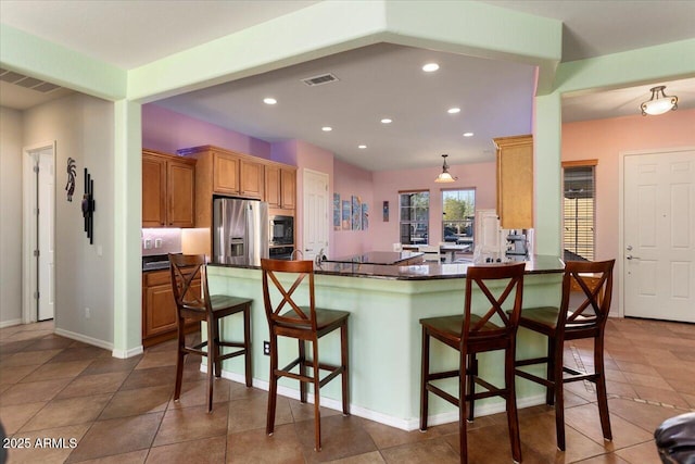 kitchen with built in microwave, a breakfast bar, stainless steel fridge, and kitchen peninsula