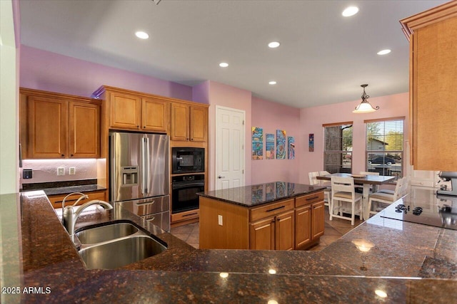 kitchen with sink, hanging light fixtures, a kitchen island, dark stone counters, and black appliances