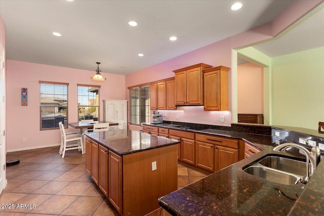 kitchen with sink, hanging light fixtures, a kitchen island, black electric cooktop, and kitchen peninsula