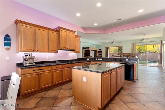 kitchen with dark stone countertops, black appliances, a kitchen island, tile patterned floors, and kitchen peninsula