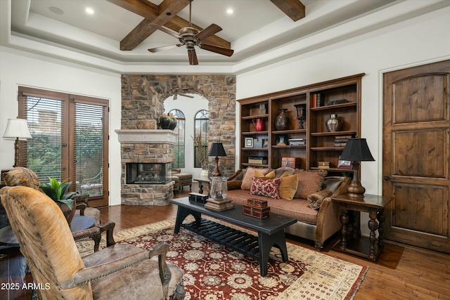 living room featuring ceiling fan, light wood-type flooring, a stone fireplace, and coffered ceiling