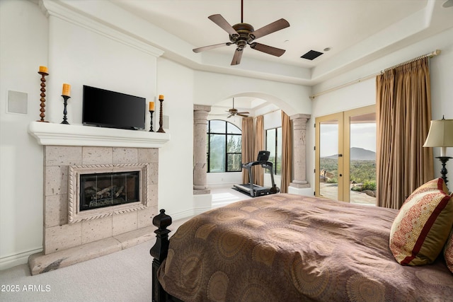 carpeted bedroom with french doors, a fireplace, access to exterior, a raised ceiling, and ceiling fan