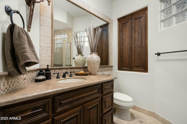 bathroom with toilet, vanity, and tasteful backsplash