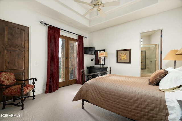 bedroom with ceiling fan, a raised ceiling, access to outside, ensuite bath, and french doors