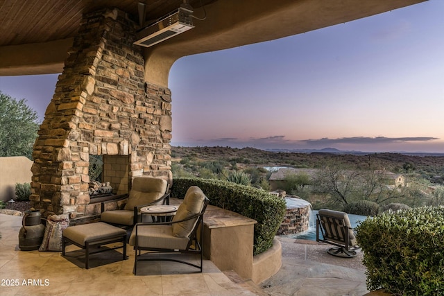 patio terrace at dusk featuring an outdoor stone fireplace