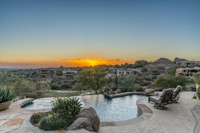 pool at dusk featuring a patio