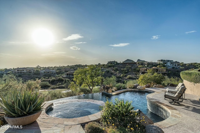 pool at dusk featuring an in ground hot tub