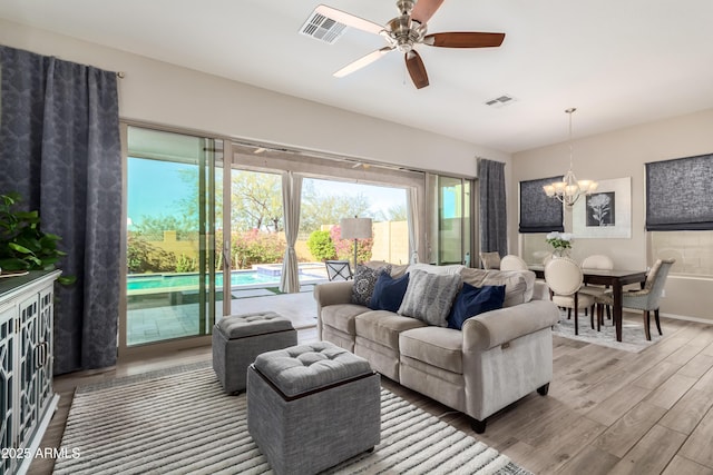 living room featuring ceiling fan with notable chandelier and hardwood / wood-style floors