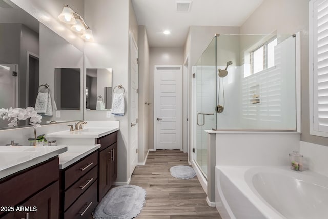 bathroom with shower with separate bathtub, wood-type flooring, and vanity