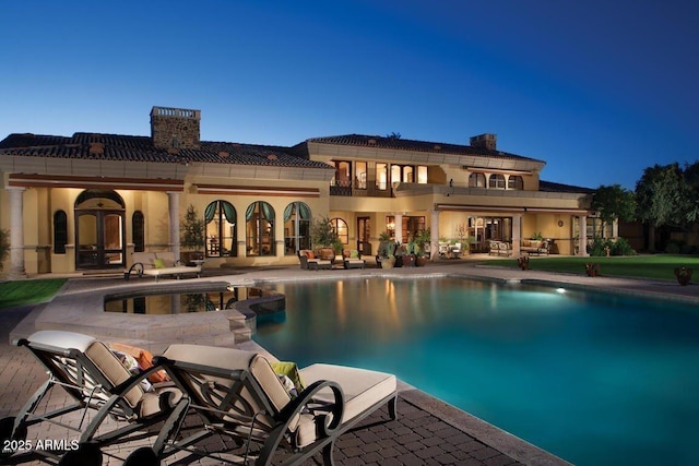 pool at dusk featuring a patio and french doors