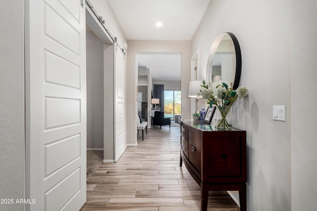 hallway featuring light wood-type flooring and a barn door