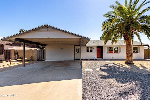 single story home featuring a carport, fence, and driveway