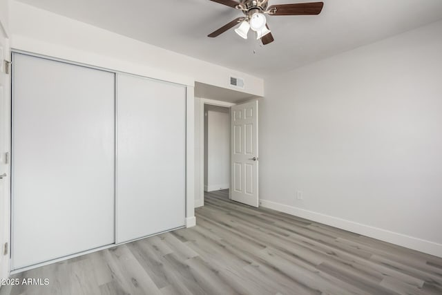 unfurnished bedroom with light wood-type flooring, baseboards, visible vents, and a closet