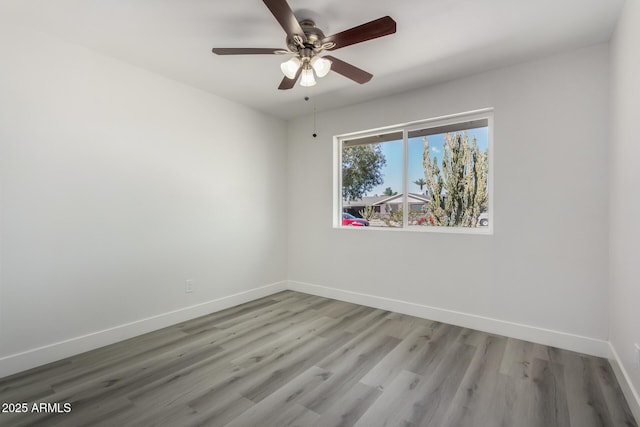 empty room with ceiling fan, baseboards, and wood finished floors