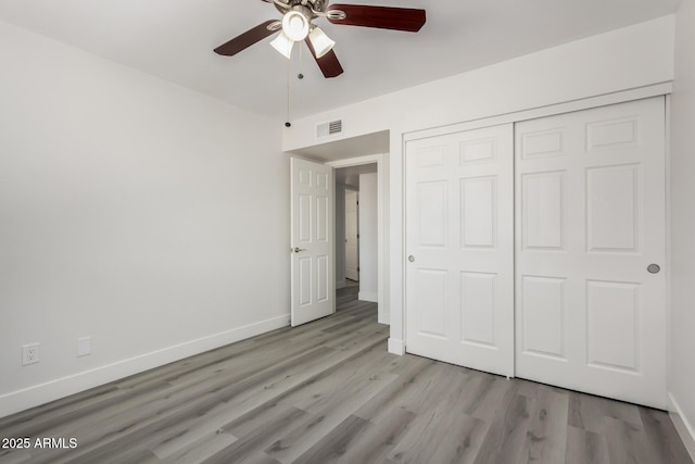 unfurnished bedroom with visible vents, a closet, baseboards, and wood finished floors