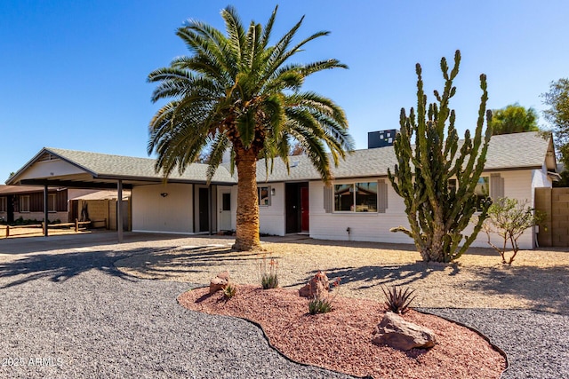 ranch-style home with a shingled roof, an attached carport, and driveway