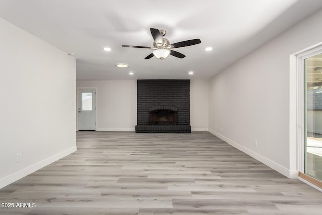 unfurnished living room featuring light wood finished floors, baseboards, a ceiling fan, a fireplace, and recessed lighting