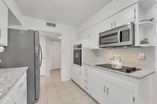 kitchen with decorative backsplash, light tile patterned flooring, white cabinets, light stone counters, and black appliances