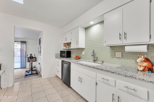 kitchen featuring stainless steel dishwasher, white cabinetry, sink, light stone counters, and light tile patterned floors