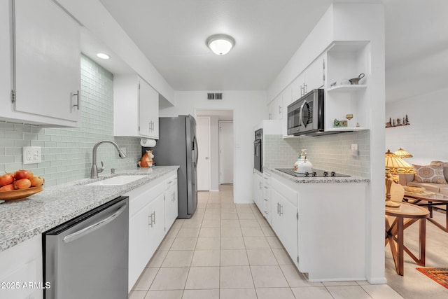 kitchen with light tile patterned floors, white cabinetry, backsplash, black appliances, and sink