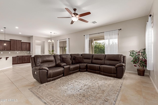 tiled living room with ceiling fan with notable chandelier