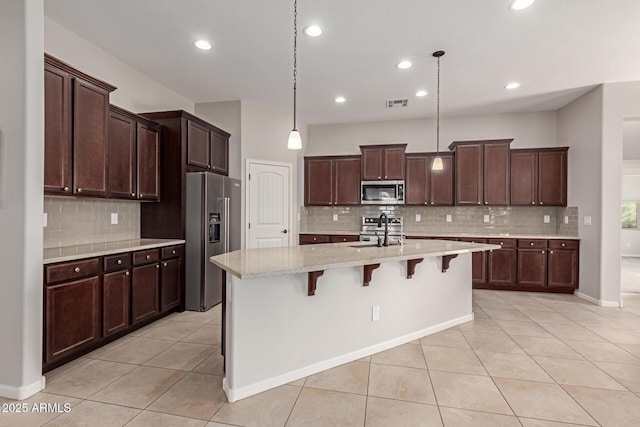 kitchen with pendant lighting, sink, an island with sink, appliances with stainless steel finishes, and a kitchen bar